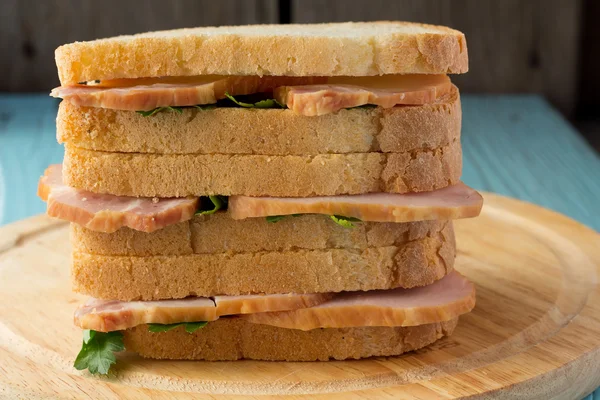 Три сэндвича с копченой свининой на деревянной тарелке — стоковое фото