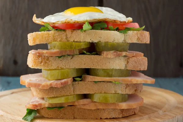 Сэндвич с копченой свининой, огурцами, помидорами и яичницей — стоковое фото