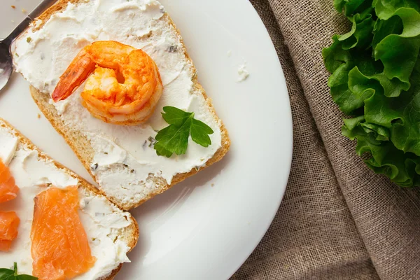 Toasts au pain de blé avec fromage à la crème, saumon fumé et crevettes — Photo