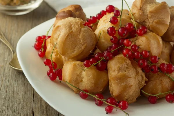 Kerma puffs ja punaherukka valkoisella lautasella — kuvapankkivalokuva