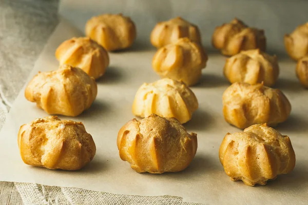 Profiteroles on cooking paper — Stock Photo, Image