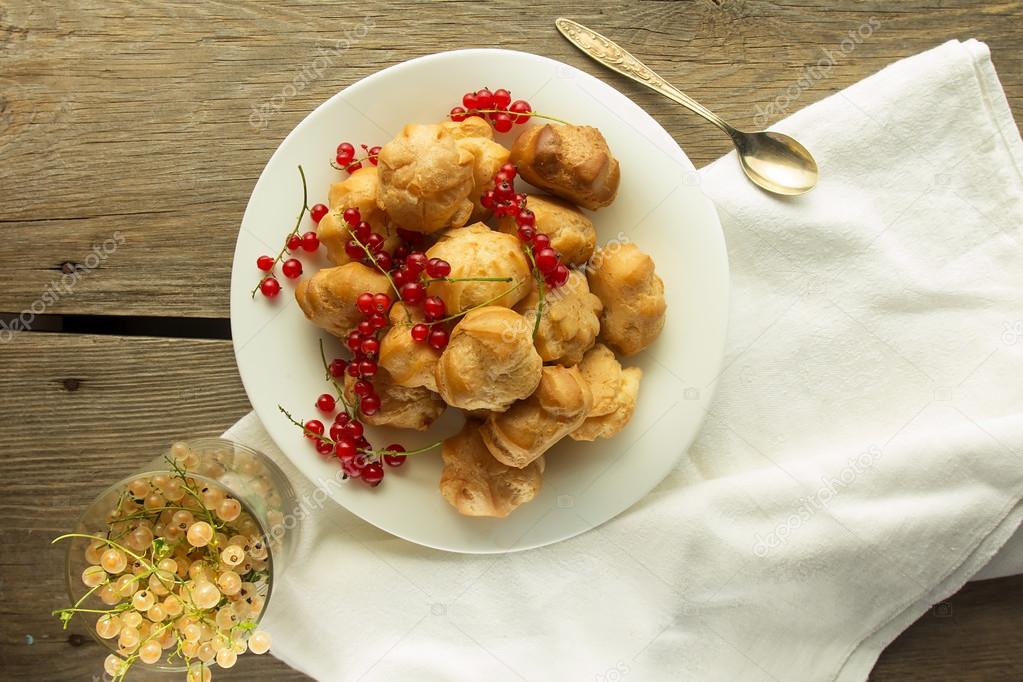 Cream puffs and red currant on white plate