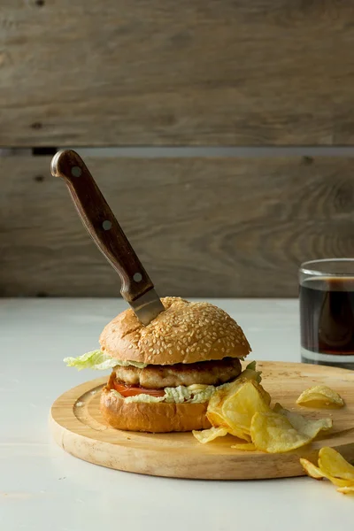 Cuchillo en hamburguesa y patatas fritas — Foto de Stock