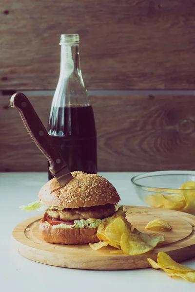 Cuchillo en hamburguesa, cola y patatas fritas — Foto de Stock