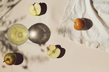 Pastel arka plan beyaz kumaş üzerinde elma ve camdan oluşan yaz dönemi kompozisyonu. Yaratıcı düzen. Tazelik kavramı. Üst Manzara. Düz yatıyordu. Boşluğu kopyala