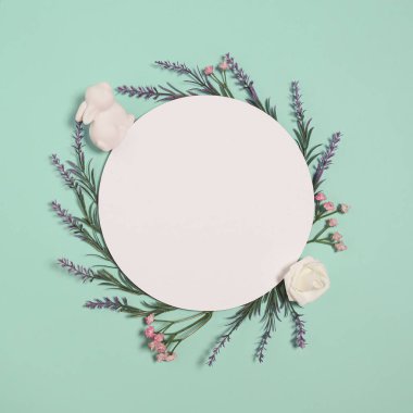 Easter composition made of easter bunny and flowers on pastel background with round shape paper card. Minimal holiday concept