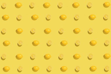 Sarı arka planda dilimlenmiş taze limonla yaratılmış yaratıcı desen. Yaz meyvesi konsepti. Asgari düzeyde. Düz güneş ışığı yatıyordu. Üst görünüm