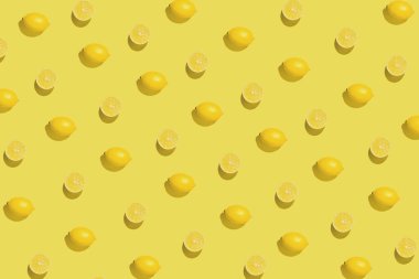 Sarı arka planda dilimlenmiş taze limonla yaratılmış yaratıcı desen. Yaz meyvesi konsepti. Asgari düzeyde. Düz güneş ışığı yatıyordu. Üst görünüm