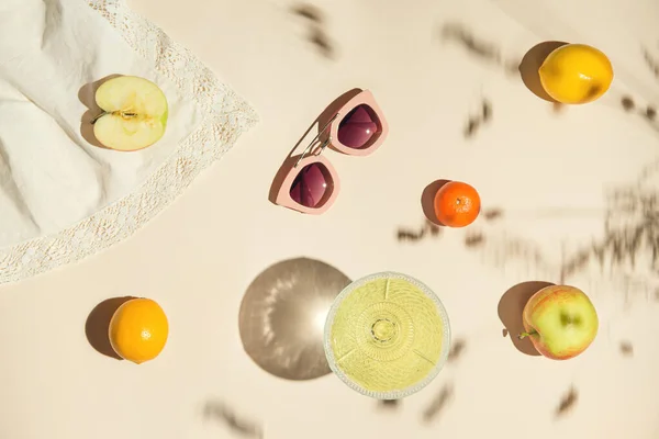 Yaz aylarında meyve, meyve suyu ve pastel arka planda güneş gözlüklerinden yapılmış beyaz bez karışımı. Yaratıcı düzen. Tazelik kavramı. Üst Manzara. Düz yatıyordu.
