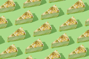 Yeşil arka planda fıstıklı cheesecake 'ten yapılmış yaratıcı desen. Sağlıklı tatlı konsepti. Asgari biçim