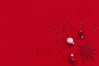 Dekoratif kar tanesi, parlak kırmızı arka planda toplar ve pullar. Noel kutlaması ve parti konsepti. Kış kompozisyonu asgari düzeyde. Düz yatıyordu. Üst Manzara. Boşluğu kopyala