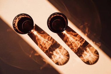 Uzun gölgeli, güneşli arka planda iki bardak su. Yaz tatili konsepti. Asgari düzeyde. Üst Manzara. Düz yatıyordu