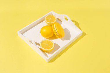 Beyaz tepside limonlu sarı badem kurabiyesi ve gölgeli güneş ışığı. Yaz tazeleme kavramı.