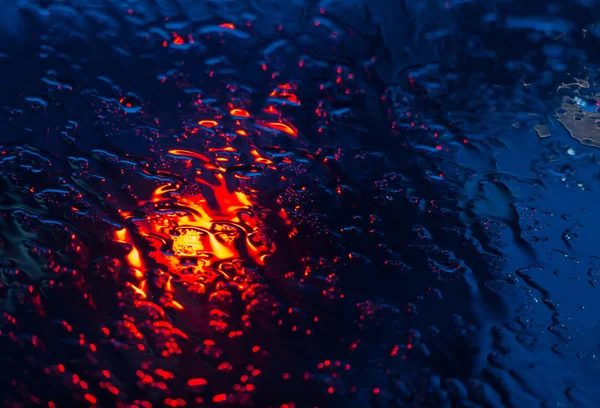 Araba windshie üzerinde yağmur damlaları ile görülen bulanık araba siluet