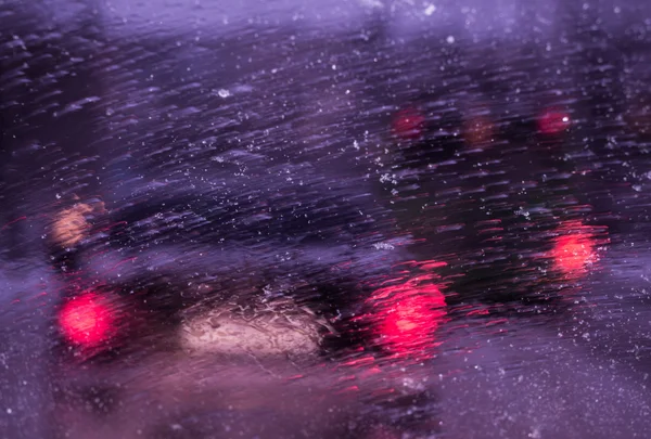 Route de la ville à travers la neige fondue sur le pare-brise de la voiture — Photo
