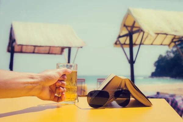 Man's hand met een glas bier in een strand-café. Vakantie de — Stockfoto