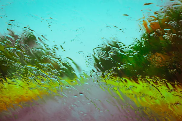 Strada vista attraverso gocce d'acqua sul parabrezza dell'auto — Foto Stock