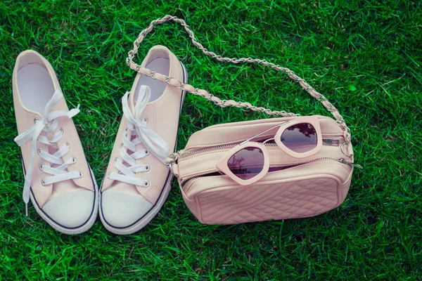 Pink sunglasses on a pink purse and sneakers