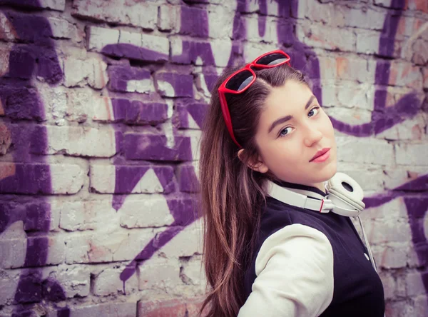 Teenage girl  with headphones near graffiti wall — Stock Photo, Image