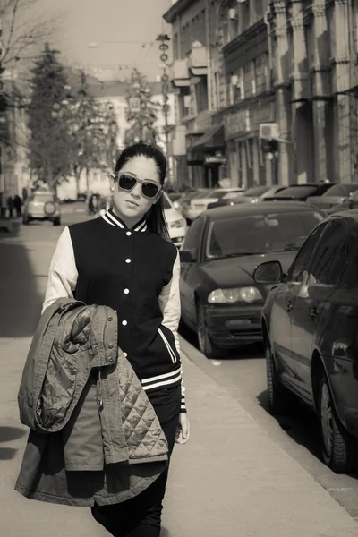 Chica con estilo en gafas de sol rojas caminando en una calle de la ciudad —  Fotos de Stock