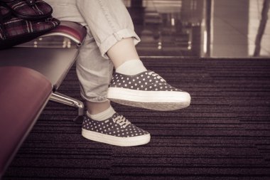 Bir sandalyede oturan bir kız. Spor ayakkabı, kot ayaklarda görünümünü