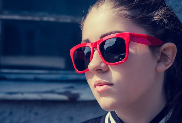 Retrato de cerca de una chica con estilo en gafas de sol rojas en una ciudad — Foto de Stock