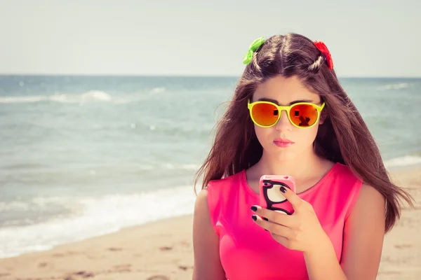 Bastante adolescente en gafas de sol y en un vestido rosa en una playa —  Fotos de Stock