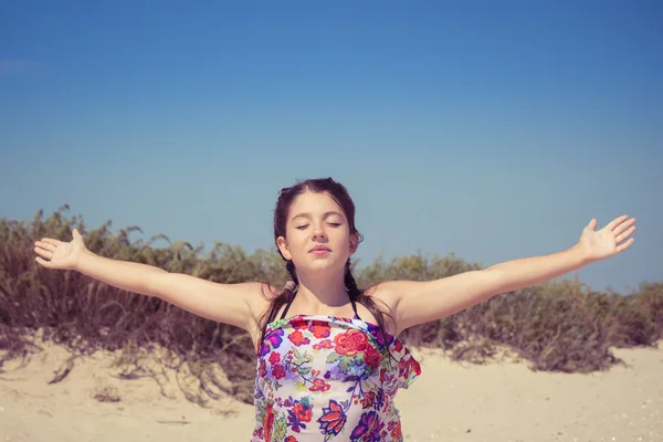 Uma menina com os olhos fechados desfrutando de sol e vento na costa do mar — Fotografia de Stock