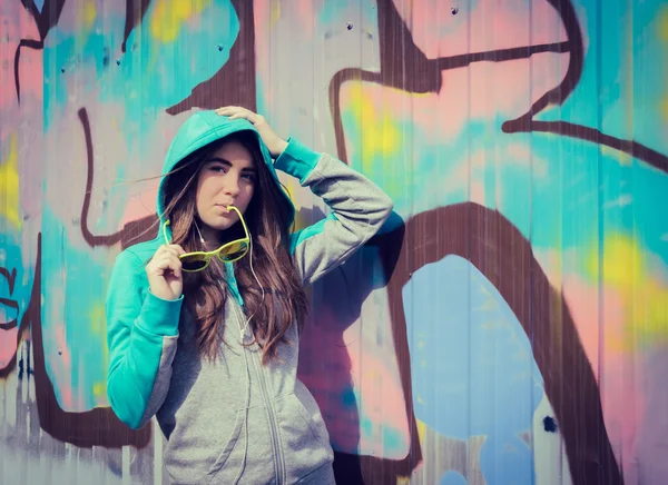 Eleganta tonårsflicka i färgglada solglasögon poserar nära graffiti — Stockfoto