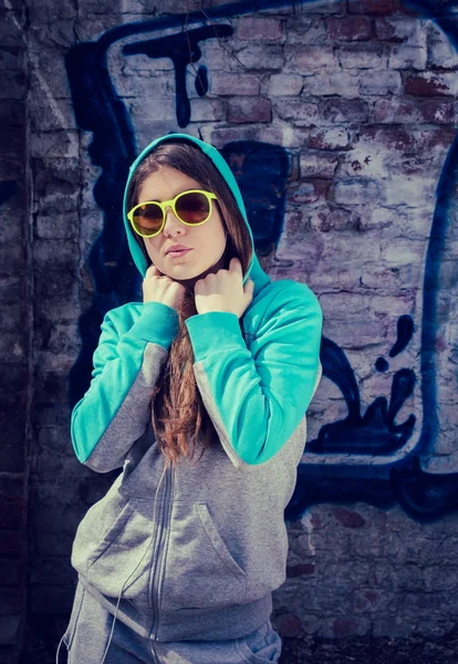 Elegante adolescente en gafas de sol de colores posando cerca de graffiti —  Fotos de Stock
