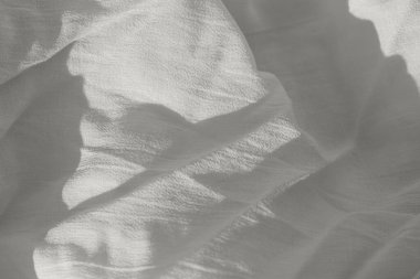 Güneş ışığı ve gölgeli doğal buruşmuş kumaş dokusundan oluşan soyut bir arka plan. 2026 yılının rengi