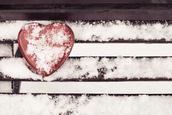 Scatola di latta a forma di cuore rosso su una panchina — Foto Stock