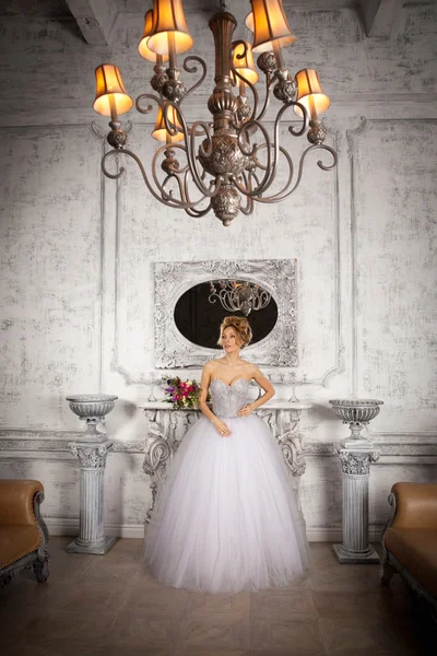 Bride standing next to the fireplace in a luxurious wedding dres — Stock Photo, Image
