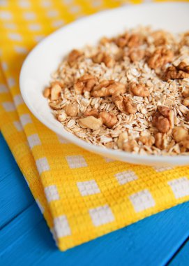 Mavi ahşap bir masa peçete dekor beyaz bir tabağa ceviz ile kuru yulaf gevreği. Fındık yulaf ezmesi. Üstten Görünüm noktası.