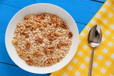 Mavi ahşap bir masa peçete dekor beyaz bir tabağa ceviz ile kuru yulaf gevreği. Fındık yulaf ezmesi. Üstten Görünüm noktası.