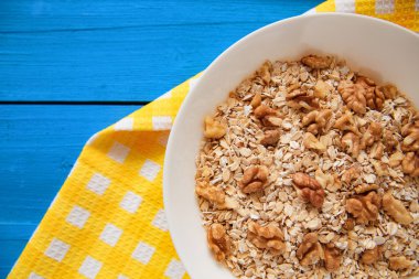 Mavi ahşap bir masa peçete dekor beyaz bir tabağa ceviz ile kuru yulaf gevreği. Fındık yulaf ezmesi. Üstten Görünüm noktası.