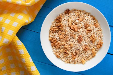 Mavi ahşap bir masa peçete dekor beyaz bir tabağa ceviz ile kuru yulaf gevreği. Fındık yulaf ezmesi. Üstten Görünüm noktası.