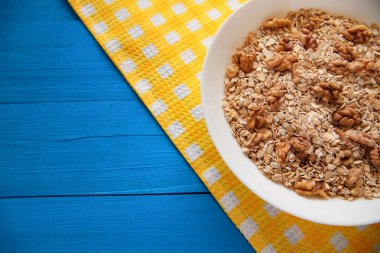 Mavi ahşap bir masa peçete dekor beyaz bir tabağa ceviz ile kuru yulaf gevreği. Fındık yulaf ezmesi. Üstten Görünüm noktası.