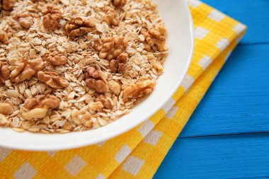 Mavi ahşap bir masa peçete dekor beyaz bir tabağa ceviz ile kuru yulaf gevreği. Fındık yulaf ezmesi. Üstten Görünüm noktası.