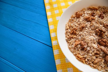 Mavi ahşap bir masa peçete dekor beyaz bir tabağa ceviz ile kuru yulaf gevreği. Fındık yulaf ezmesi. Üstten Görünüm noktası.