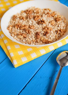 Mavi ahşap bir masa peçete dekor beyaz bir tabağa ceviz ile kuru yulaf gevreği. Fındık yulaf ezmesi. Üstten Görünüm noktası.
