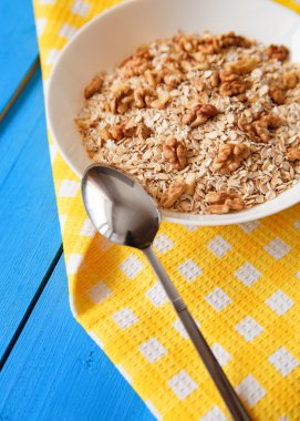 Mavi ahşap bir masa peçete dekor beyaz bir tabağa ceviz ile kuru yulaf gevreği. Fındık yulaf ezmesi. Üstten Görünüm noktası.