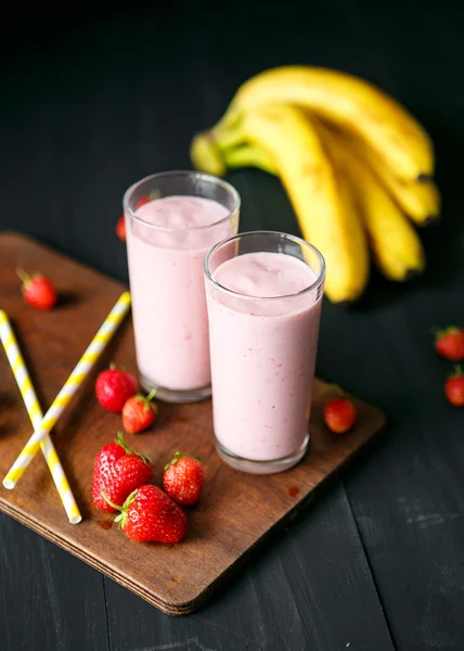 Smoothie de morango e banana no vidro sobre fundo preto — Fotografia de Stock