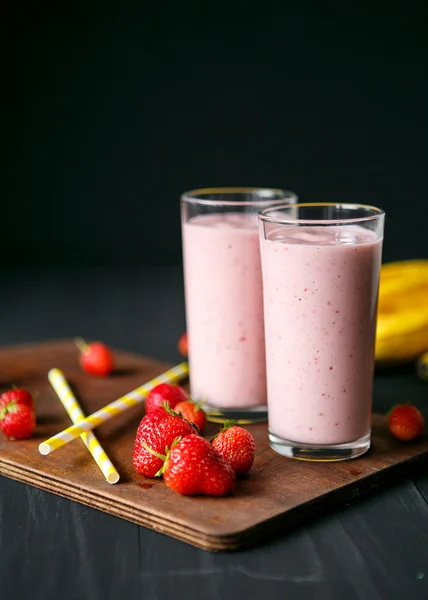 Smoothie de morango e banana no vidro sobre fundo preto — Fotografia de Stock