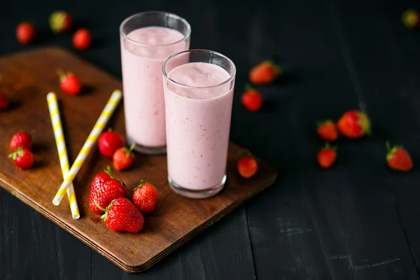 Smoothie de morango e banana no vidro sobre fundo preto — Fotografia de Stock