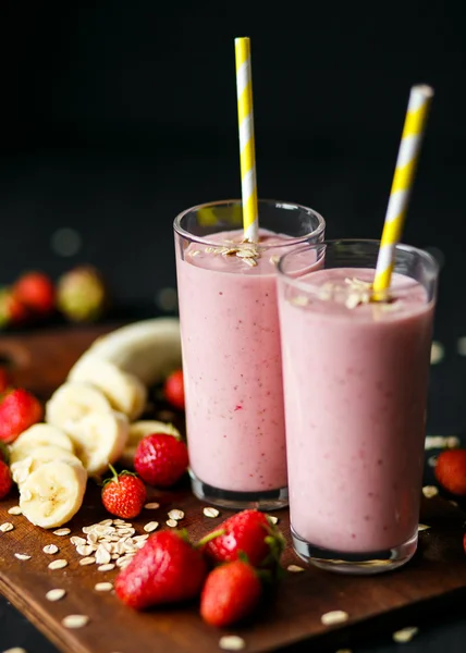 Smoothie de morango e banana no vidro sobre fundo preto — Fotografia de Stock