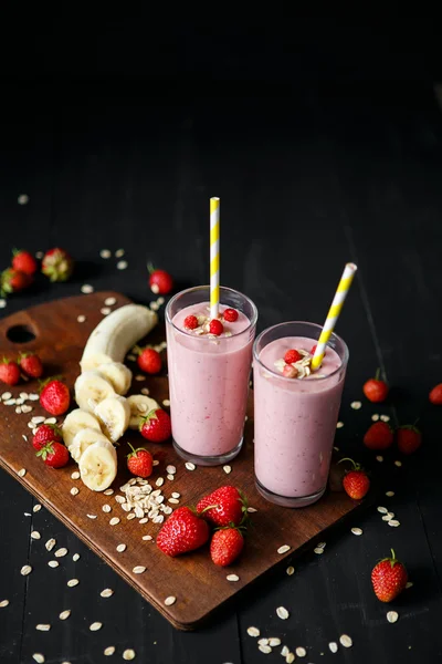 Smoothie de morango e banana no vidro sobre fundo preto — Fotografia de Stock