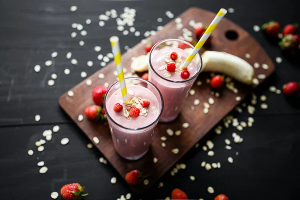 Smoothie de morango e banana no vidro sobre fundo preto — Fotografia de Stock