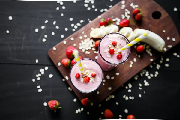 Erdbeer-Bananen-Smoothie im Glas auf schwarzem Hintergrund — Stockfoto