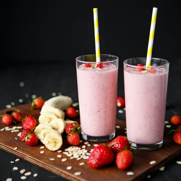 Smoothie de morango e banana no vidro sobre fundo preto — Fotografia de Stock